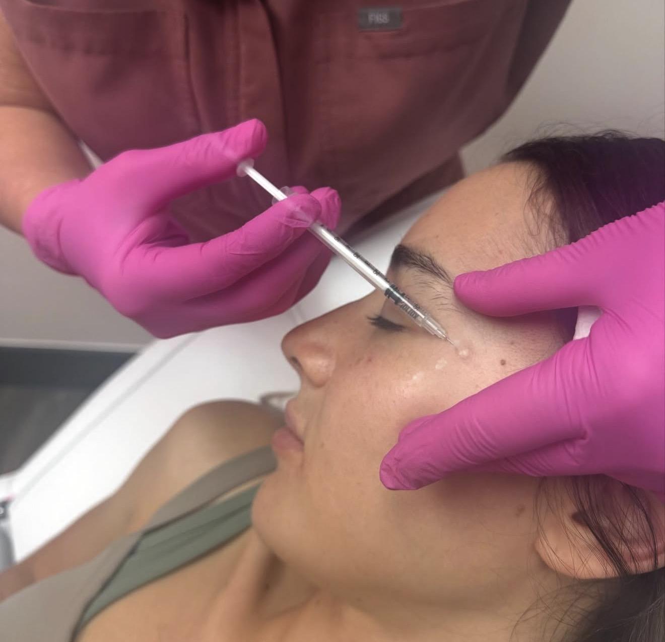Aesthetician injecting botox into a client's face